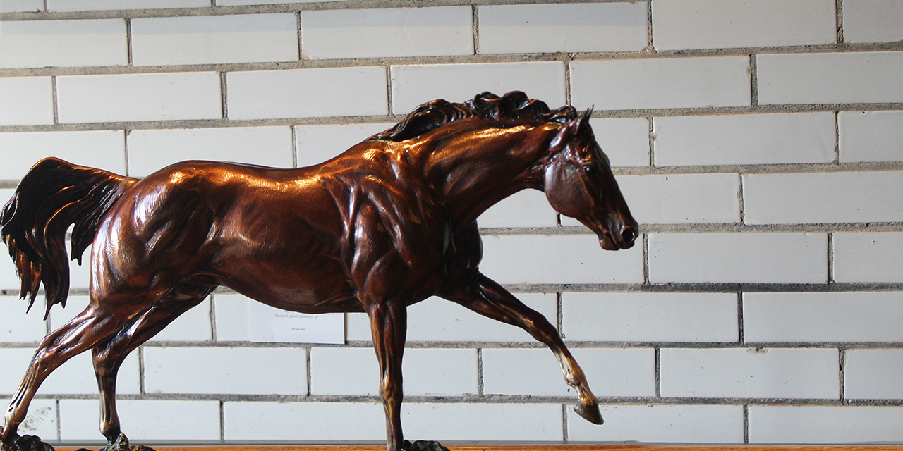 Closeup of a horse statuette against a ceramic tile wall